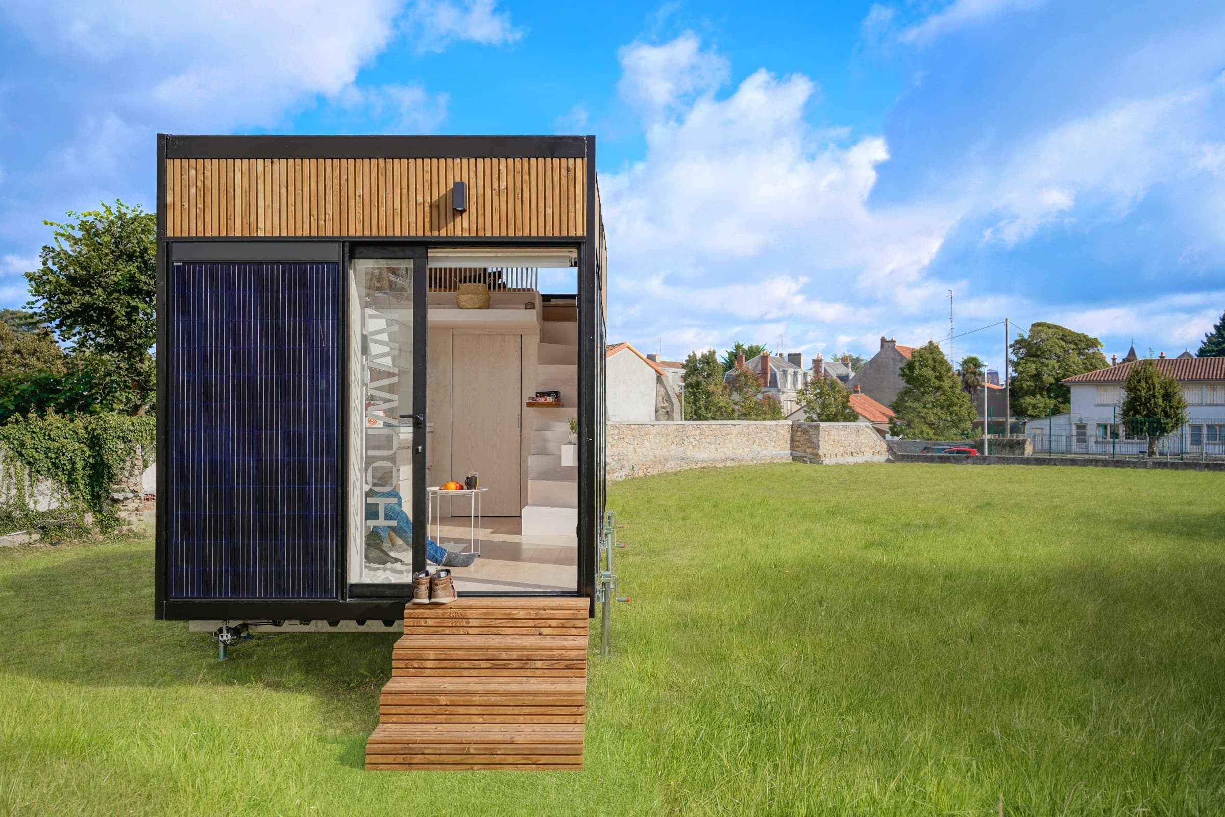 Module Hoummi posé sur une pelouse, panneau photovoltaïque intégré en façade et baie coulissante ouverte sur la pièce de vie