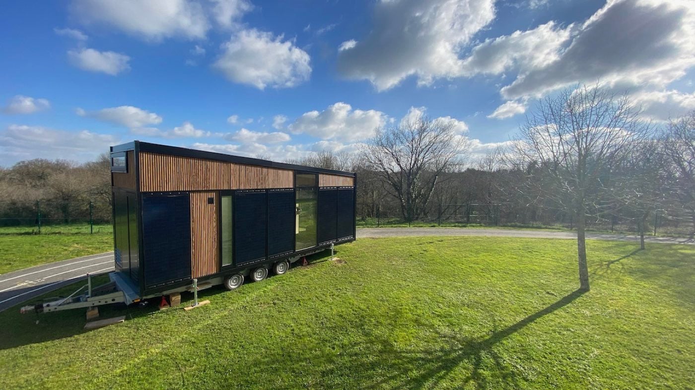 Module à façade entièrement photovoltaïque posé sur sa remorque au bord d'une pelouse