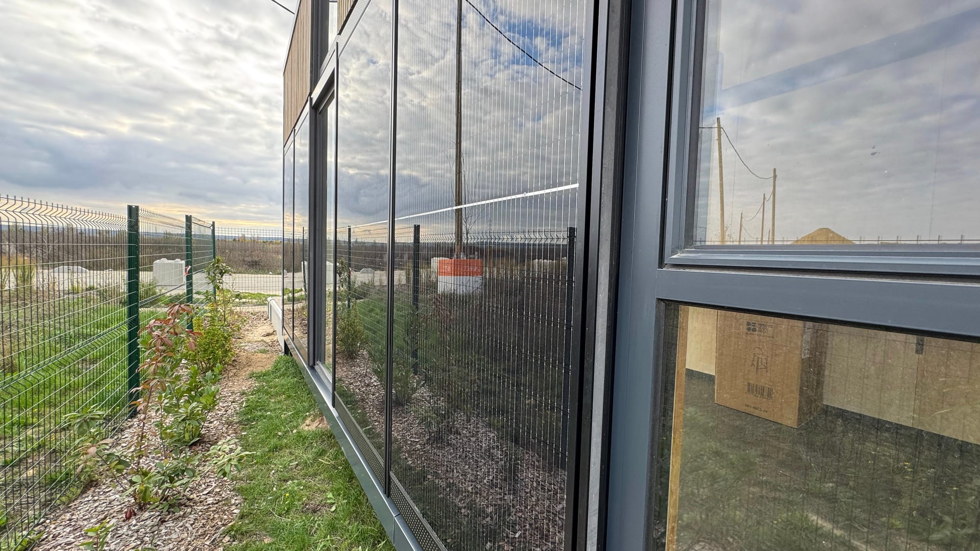 Façade latérale d'un module Hoummi : lés photovoltaïques verticaux toute hauteur surmontés du bardage bois de l'attique, au couchant