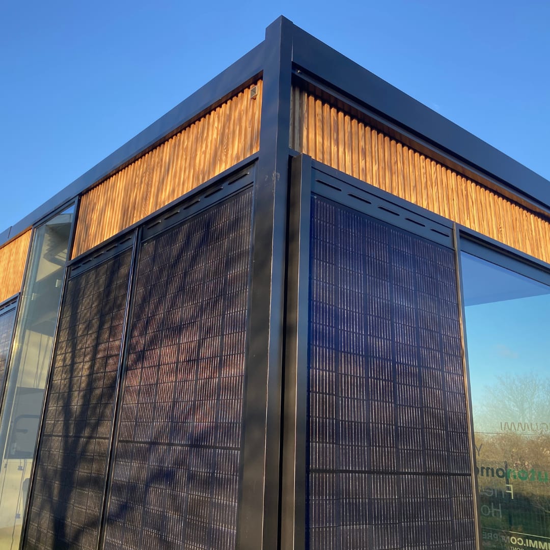 Angle d'un module Hoummi en contre-plongée : grands vitrages, panneaux photovoltaïques de façade et bardage bois en partie haute