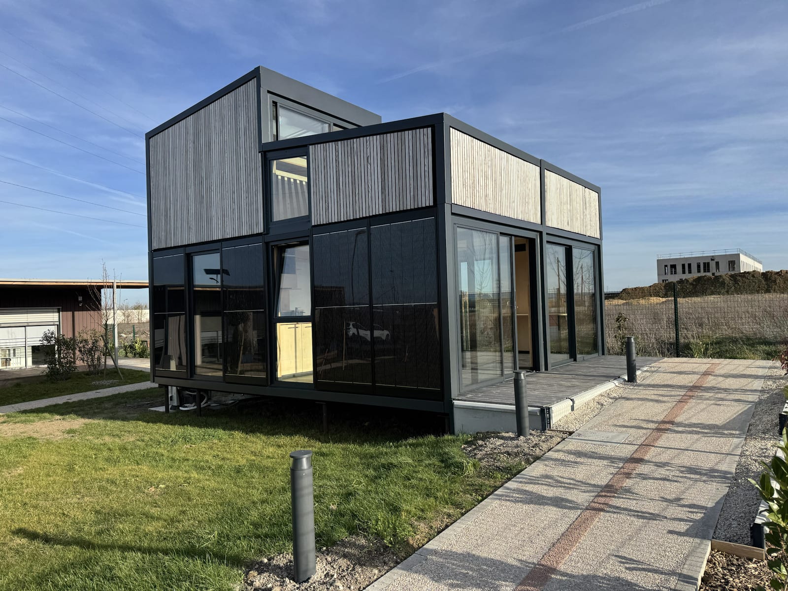 Module Hoummi à deux niveaux porté par des pilotis, bardage vertical et grandes baies